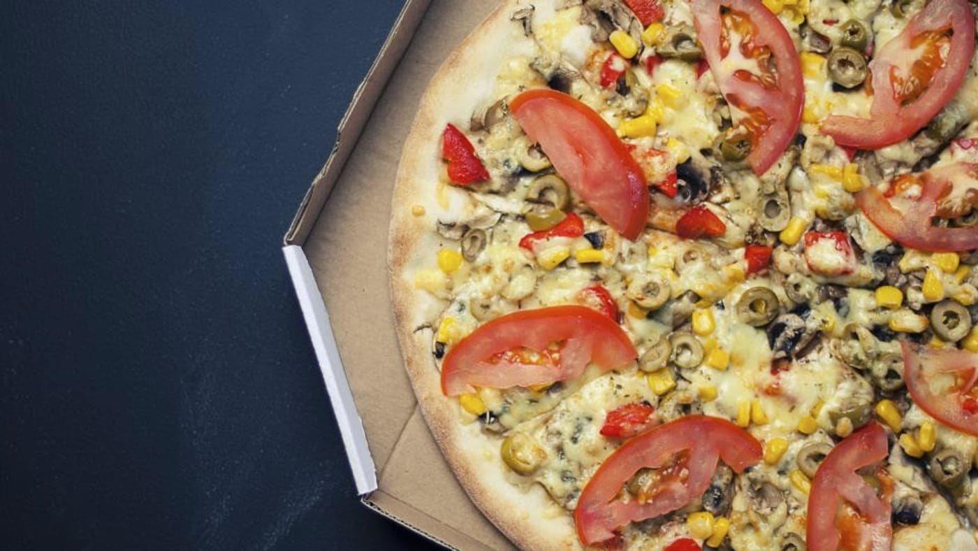 Pizza going into a wood-fired oven